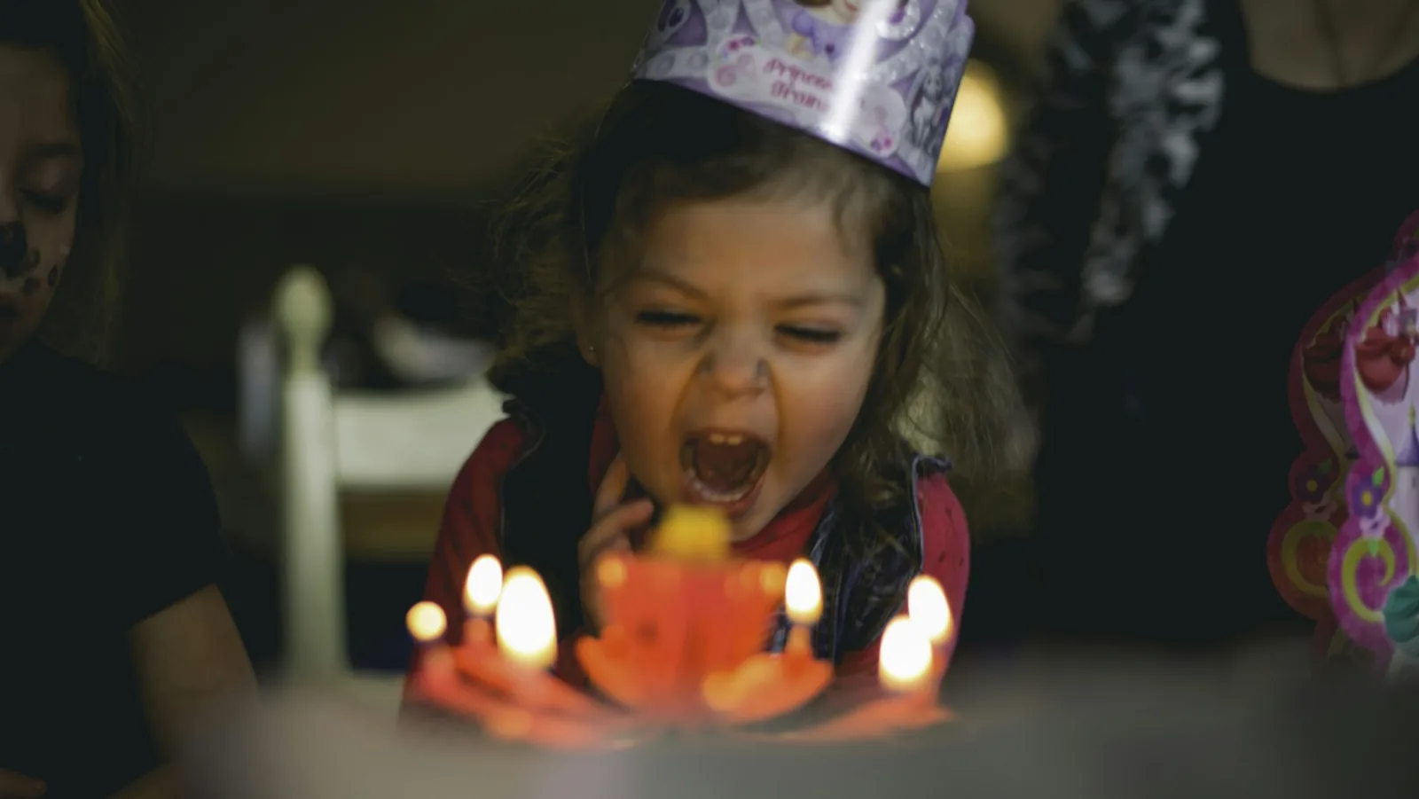 A toddler blowing out birthday candles