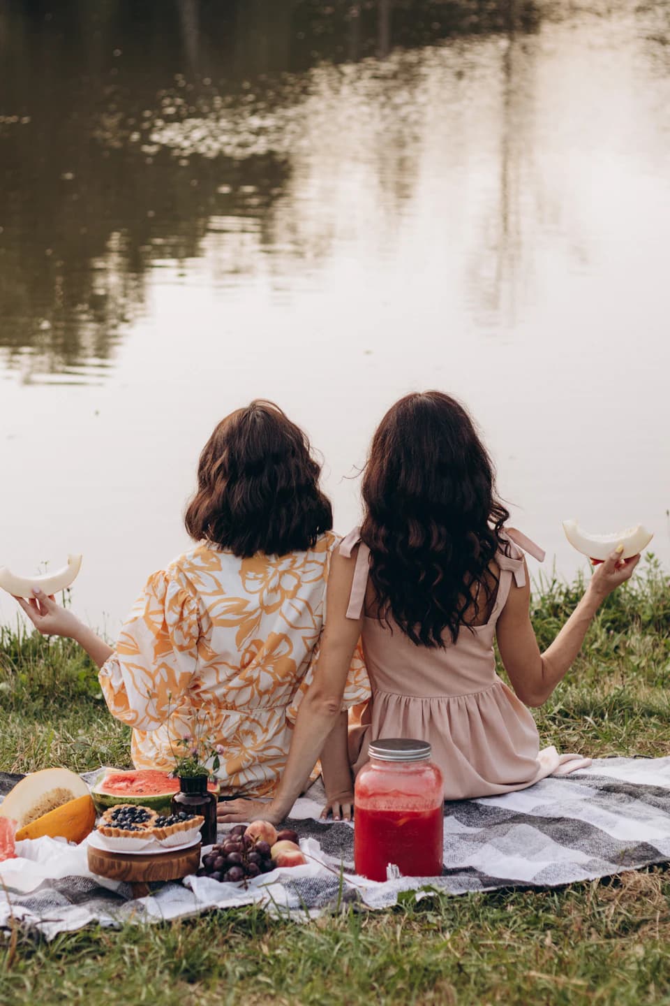 Friends sitting together beside calm water